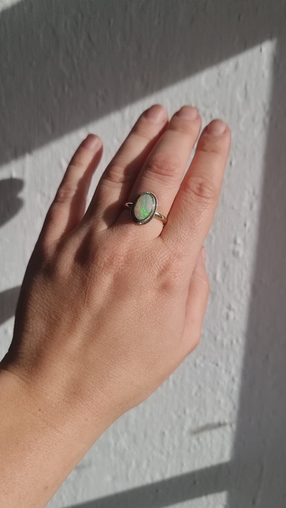 Large Australian Opal Gold Ring being worn in the sun. The hand moves to showe the magical rainbow of colours.