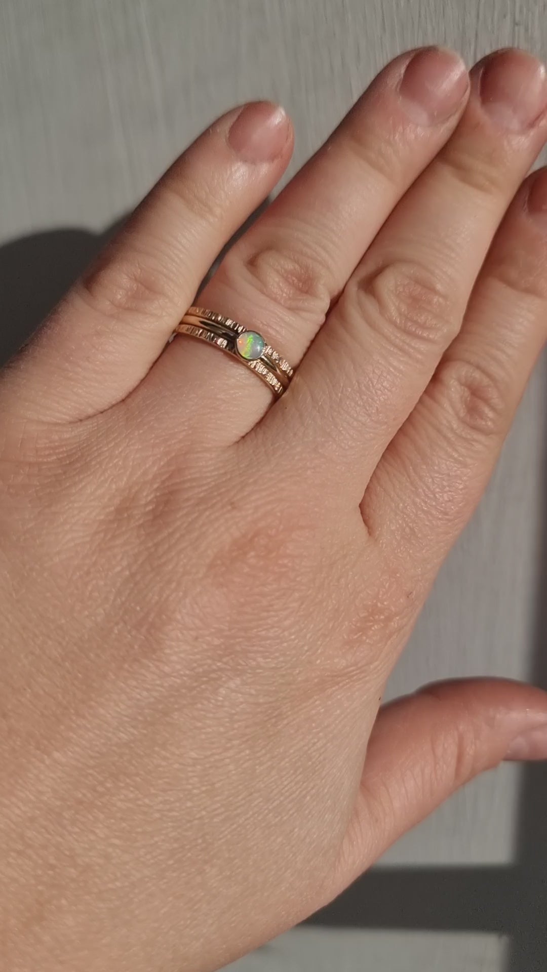 Crystal Opal Gold Stack Ring Set worn in bright sunlight, capturing the shifting colours of the Australian Crystal Opal and the intricate texture of the Silver rings