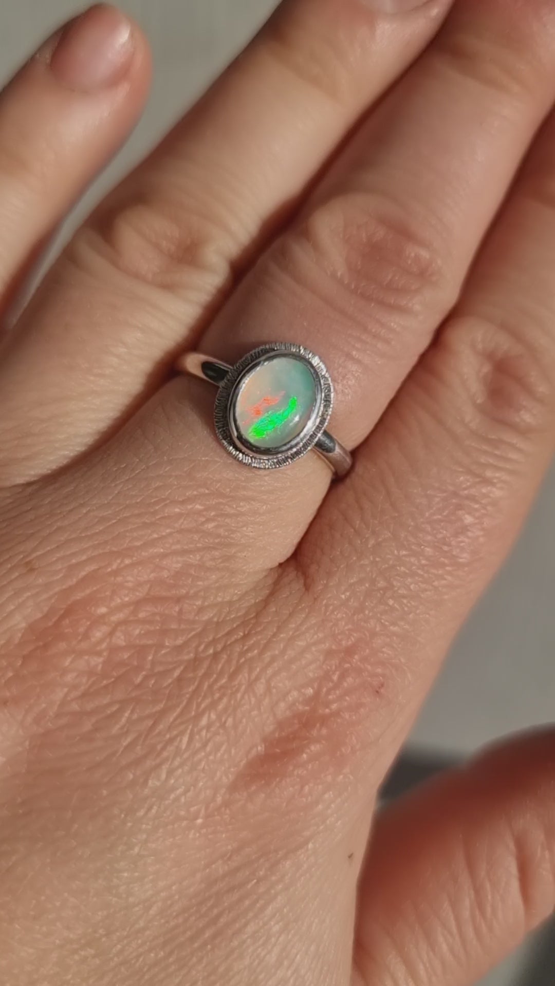 Close-up video of The Silver Aura Stained Glass Opal Silver Ring worn in the sun, capturing the shifting play of colours in the Crystal Opal against the Sterling Silver band.